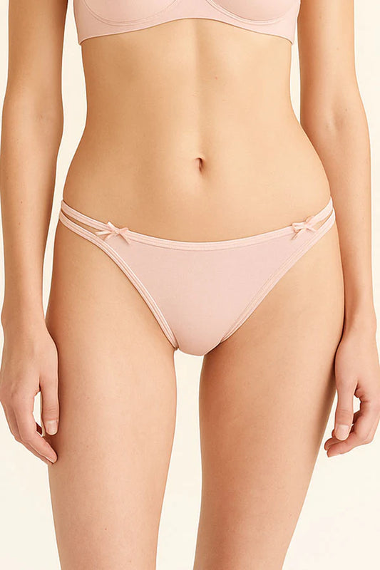 Person wearing a light pink bikini on a beige background