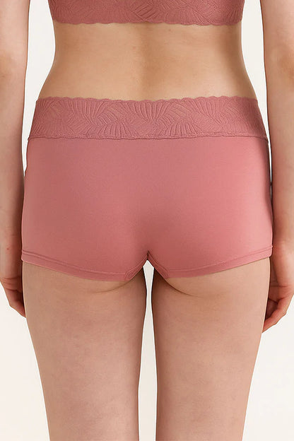 Person wearing a pair of pink MauveGlow shorts with a subtle pattern on a plain background