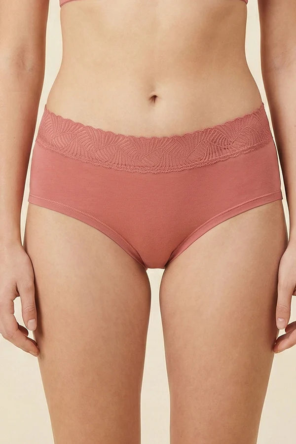 Person wearing a pair of pink MauveGlow underwear with lace trim on a beige background