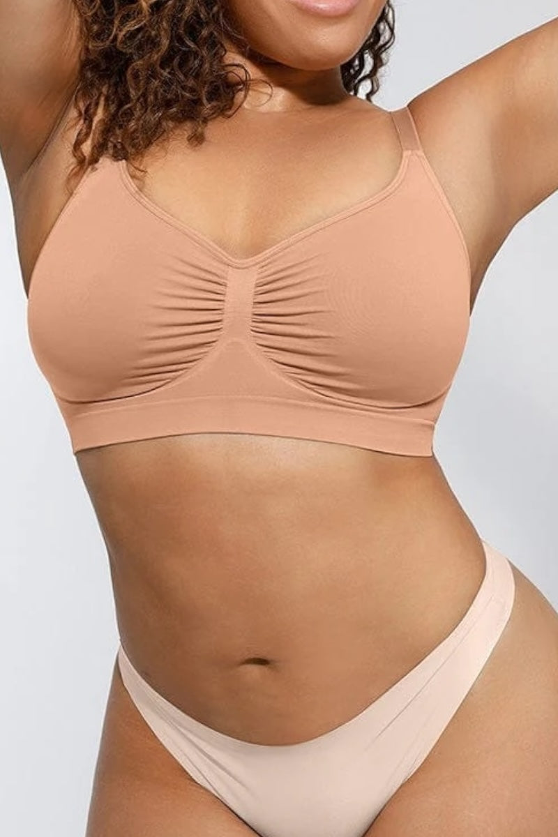 Person wearing a beige bralette on a plain background