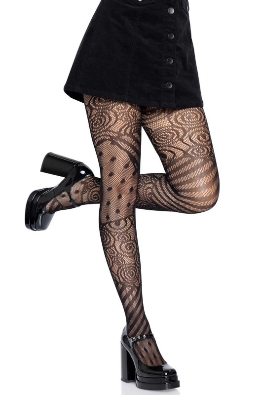 Black patterned tights with a swirl and polka dot design, shown on a model wearing a black skirt and black platform Mary Jane heels against a white background.