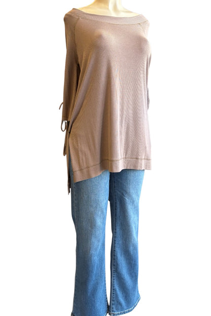 A taupe off-the-shoulder knit top with side ties, styled with blue jeans on a mannequin torso against a white background.