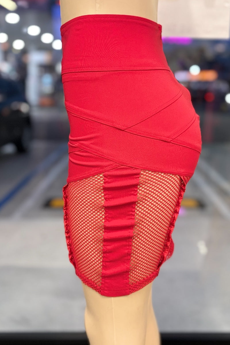 Red skirt with fishnet panels worn by a person, blurred indoor background