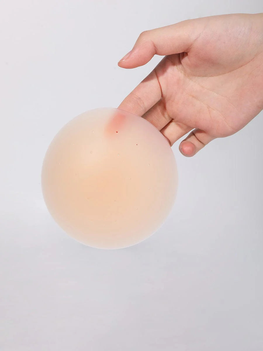 Hand holding a beige silicone pad against a light gray background