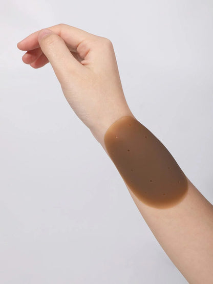 Hand with a brown nipple cover on a light gray background