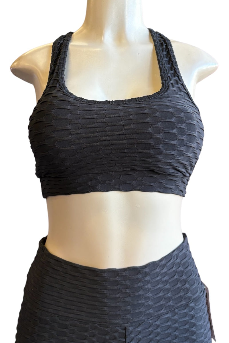 A black textured two-piece activewear set consisting of a scoop-neck sports bra and matching high-waisted shorts, displayed on a mannequin torso against a white background.