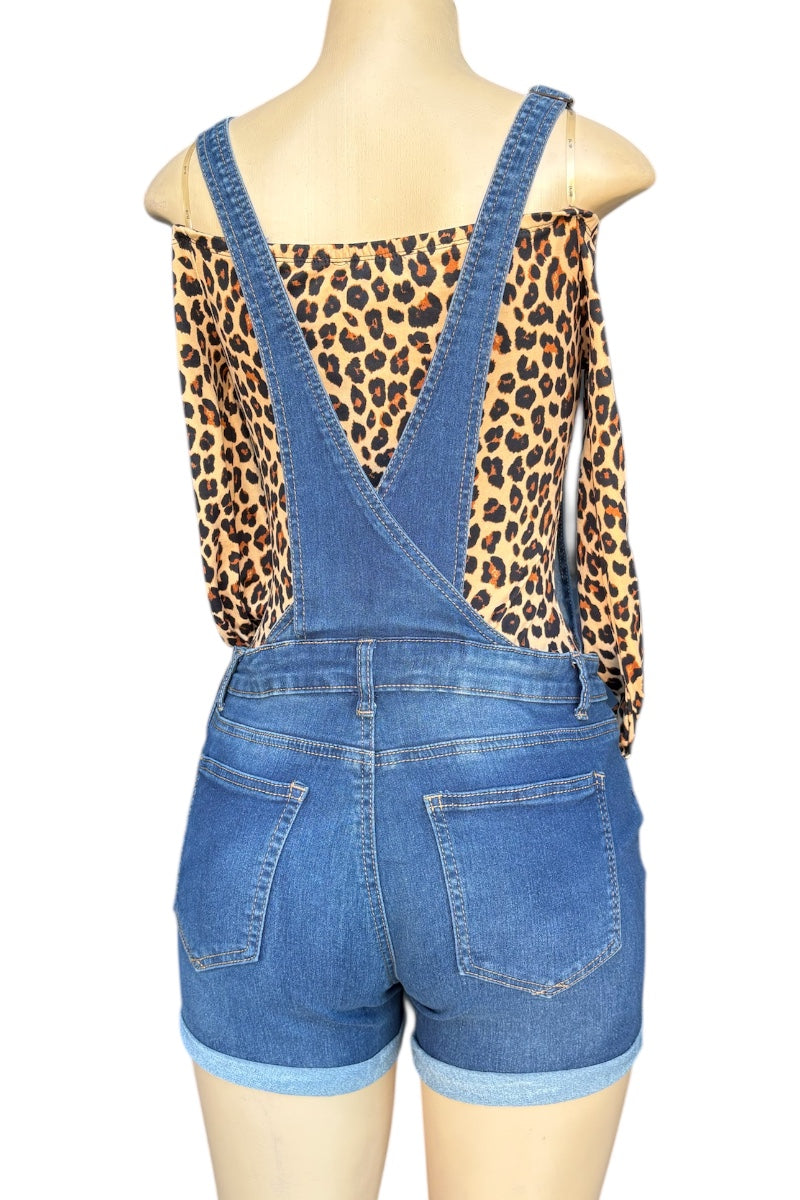 Blue denim overalls worn by a mannequin with a leopard print top underneath on a white background