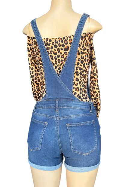 Blue denim overalls worn by a mannequin with a leopard print top underneath on a white background