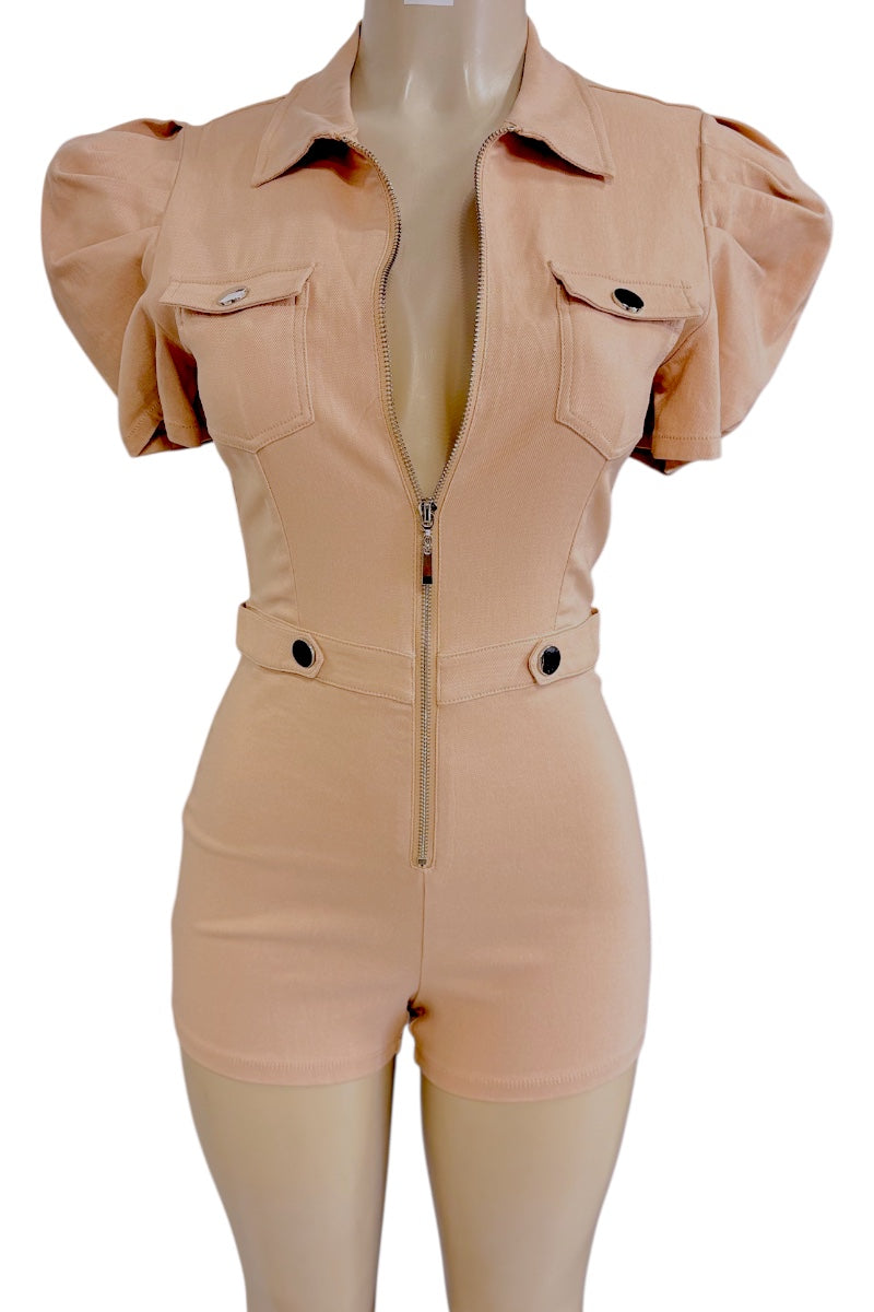 A beige-colored short romper with puff sleeves, a front zipper, and flap chest pockets, displayed on a mannequin against a white background.