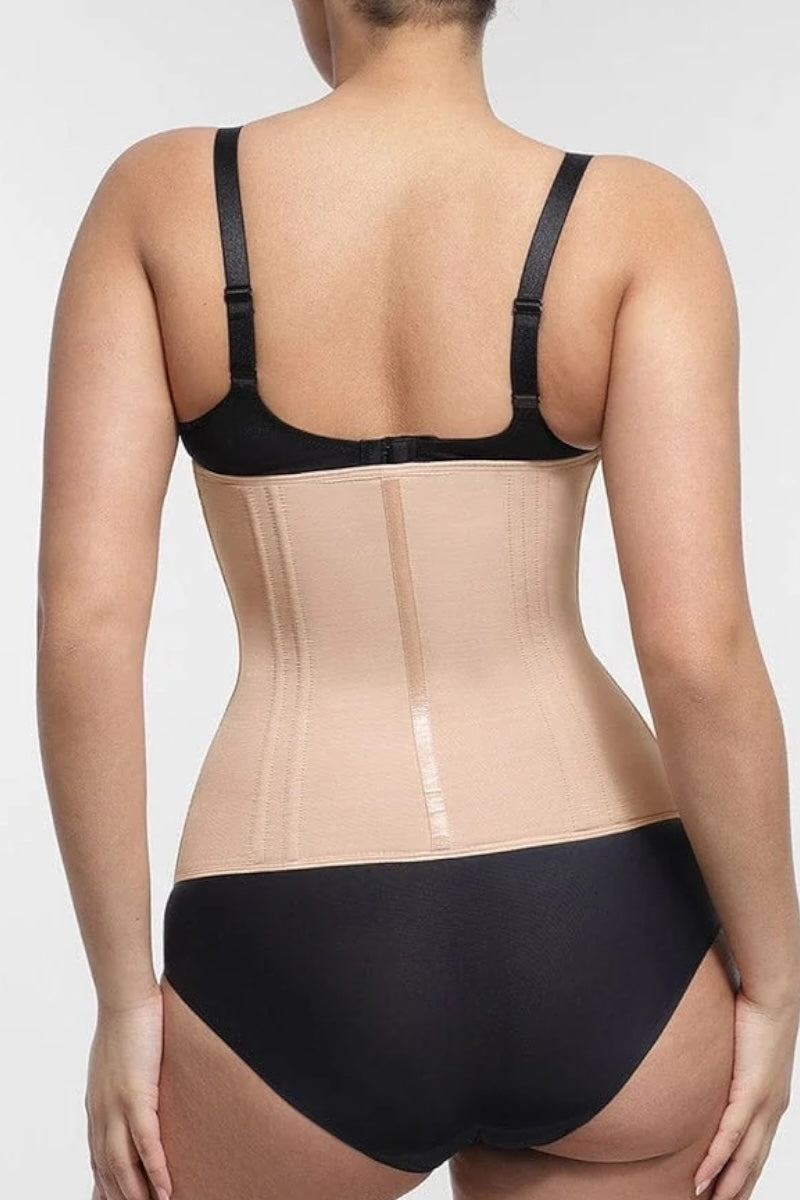 Person wearing a black bra and beige waist trainer on a white background