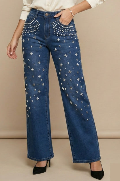 Blue jeans with decorative patterns worn by a person on a beige background