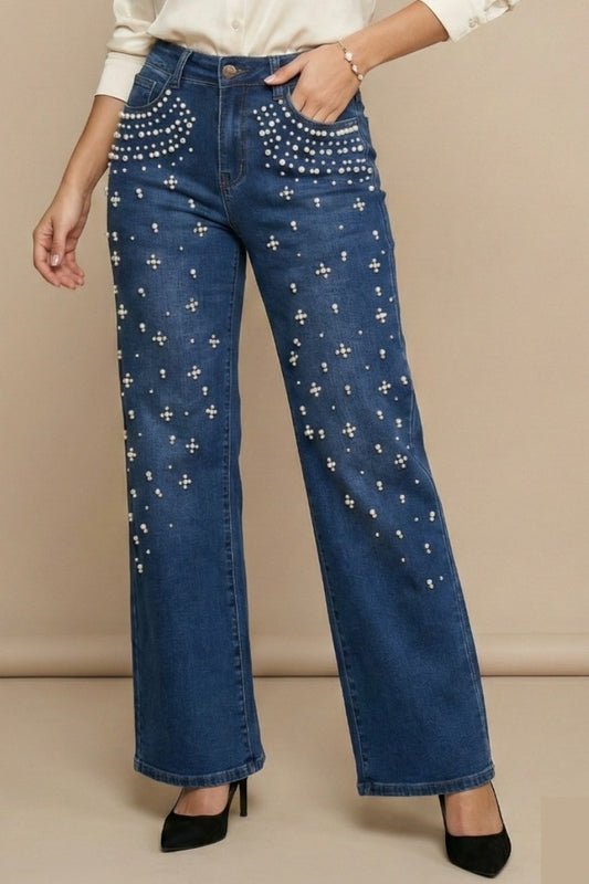 Blue jeans with decorative patterns worn by a person on a beige background