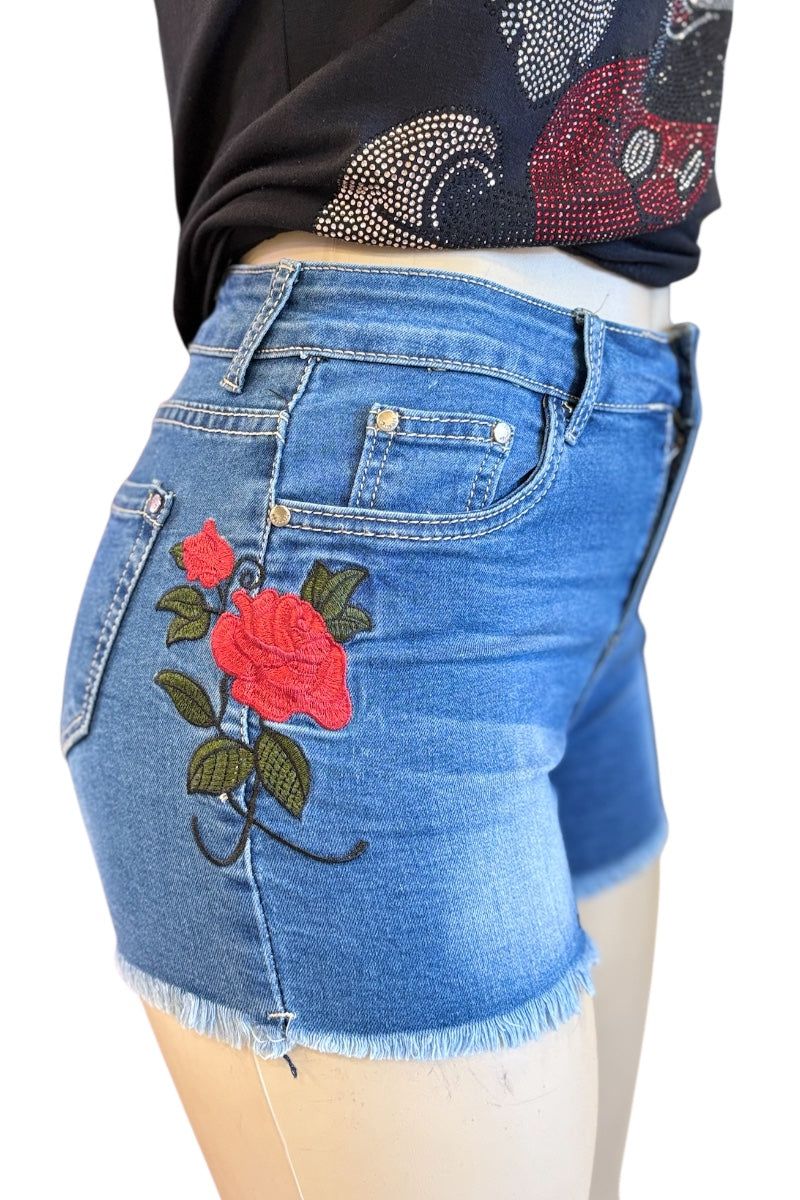 Blue denim shorts with floral embroidery on a mannequin.
