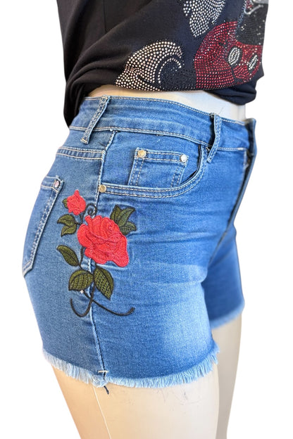 Blue denim shorts with floral embroidery on a mannequin.