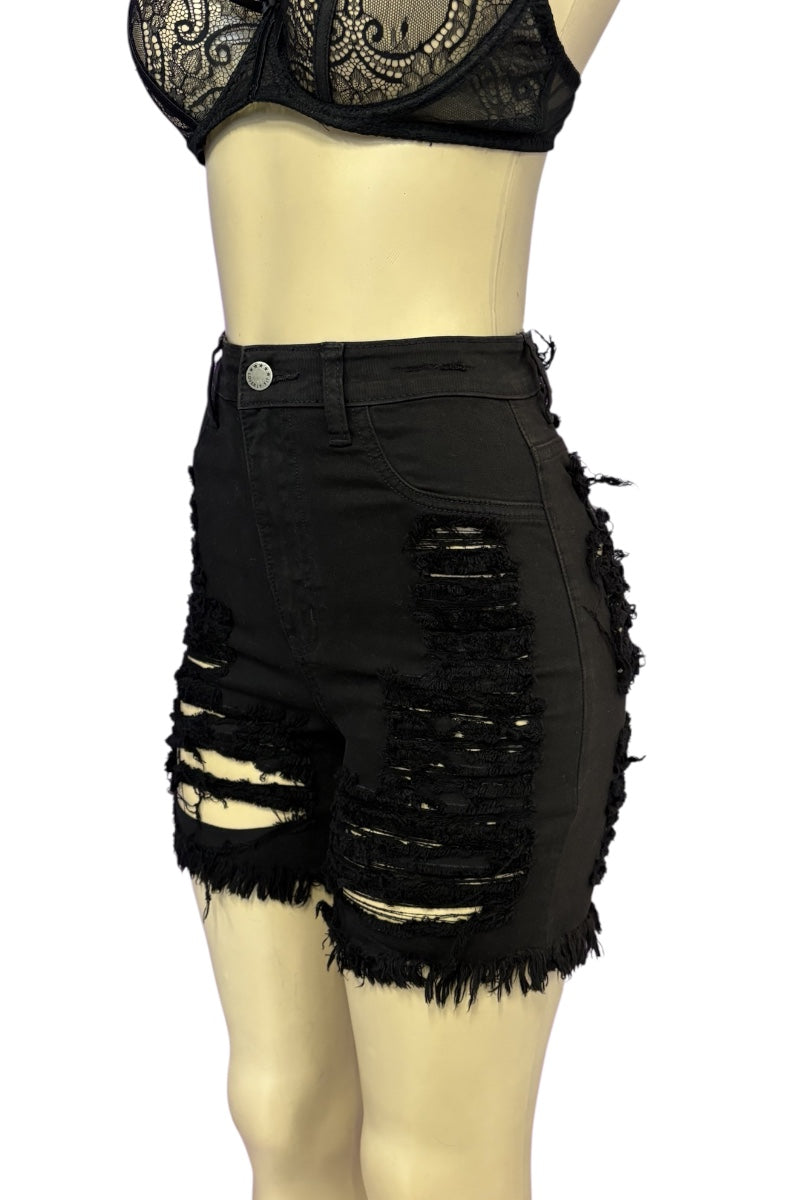 Black high-waisted distressed denim shorts with heavy rips and frayed hems, displayed on a beige mannequin torso against a white background.