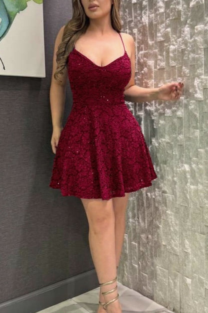 Woman wearing a burgundy lace dress standing against a textured wall.