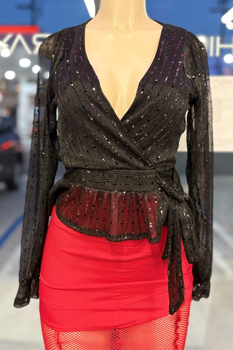 Black sequined top with a deep neckline and red skirt on a mannequin against a blurred indoor background.