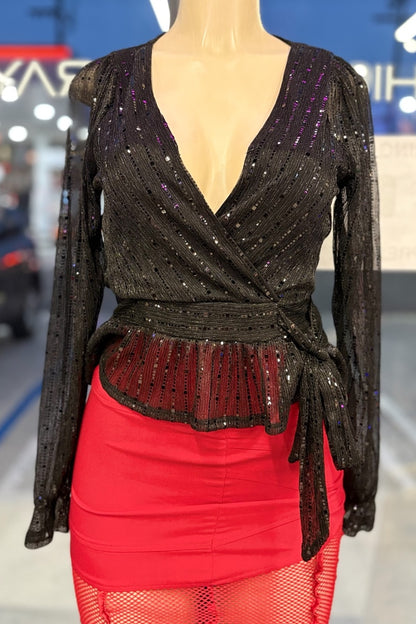 Black sequined top with a deep neckline and red skirt on a mannequin against a blurred indoor background.