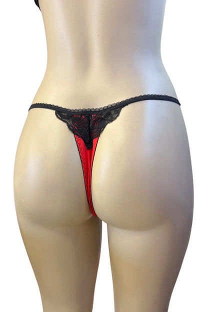 Red and black lace thong underwear shown from the back on a beige mannequin torso against a white background.