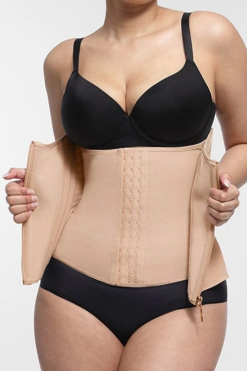 Person wearing a black bra and beige waist trainer on a white background