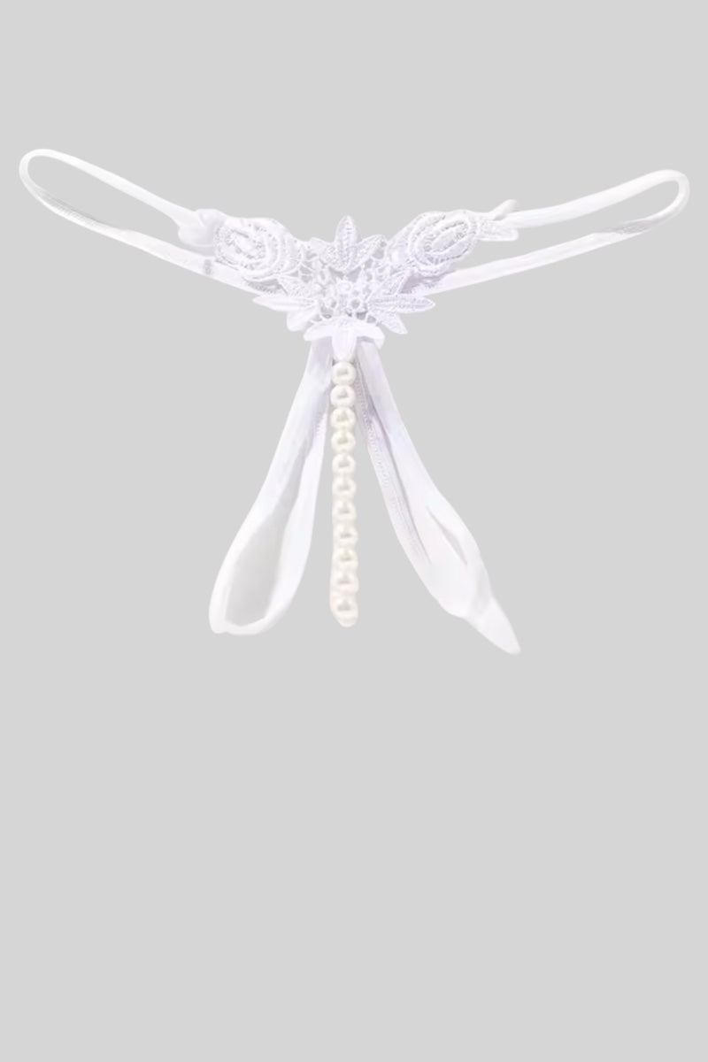 A white thong with a central floral applique, a dangling pearl bead strand, and thin elastic leg straps, shown against a solid gray background.