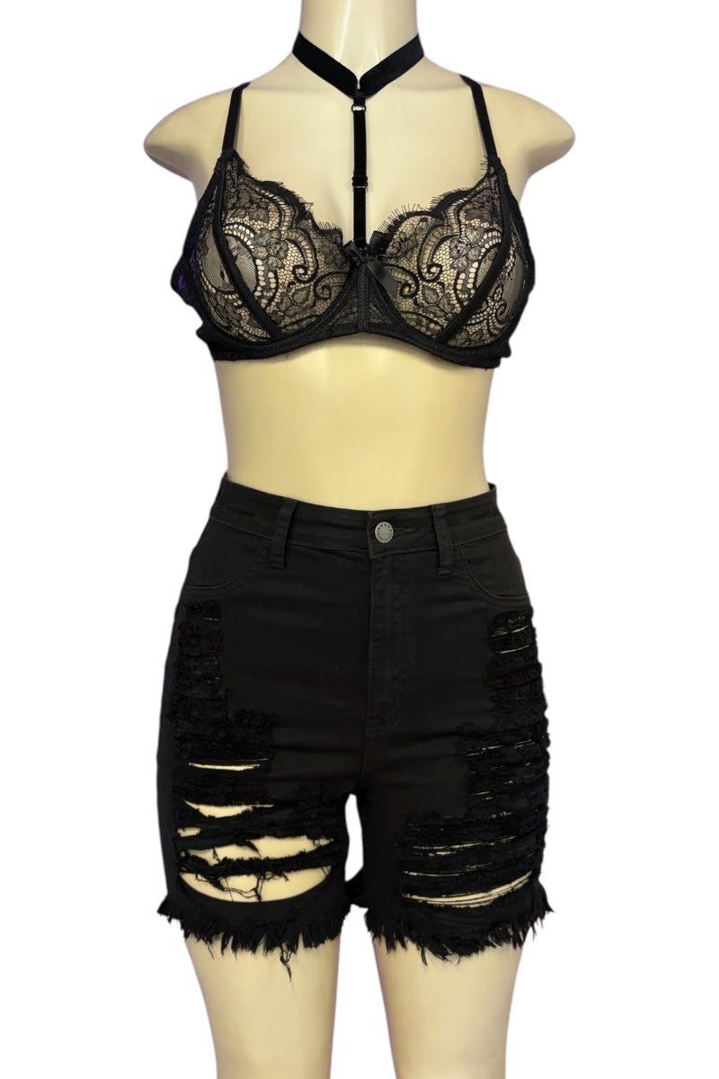 A two-piece women's outfit displayed on a beige mannequin, featuring a black lace halter bralette and matching high-waisted black distressed denim shorts with ripped details and frayed hems.