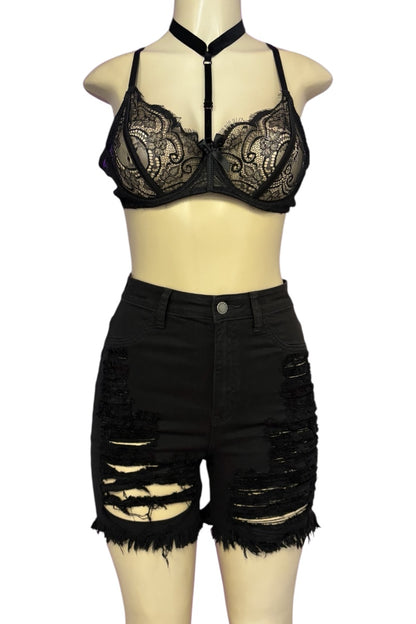 A two-piece women's outfit displayed on a beige mannequin, featuring a black lace halter bralette and matching high-waisted black distressed denim shorts with ripped details and frayed hems.