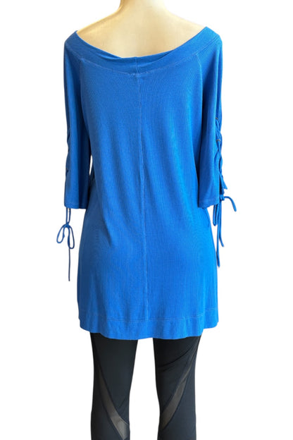 A bright blue knit tunic top with an off-the-shoulder neckline, three-quarter sleeves, and side lace-up ties, displayed on a mannequin torso against a white background.