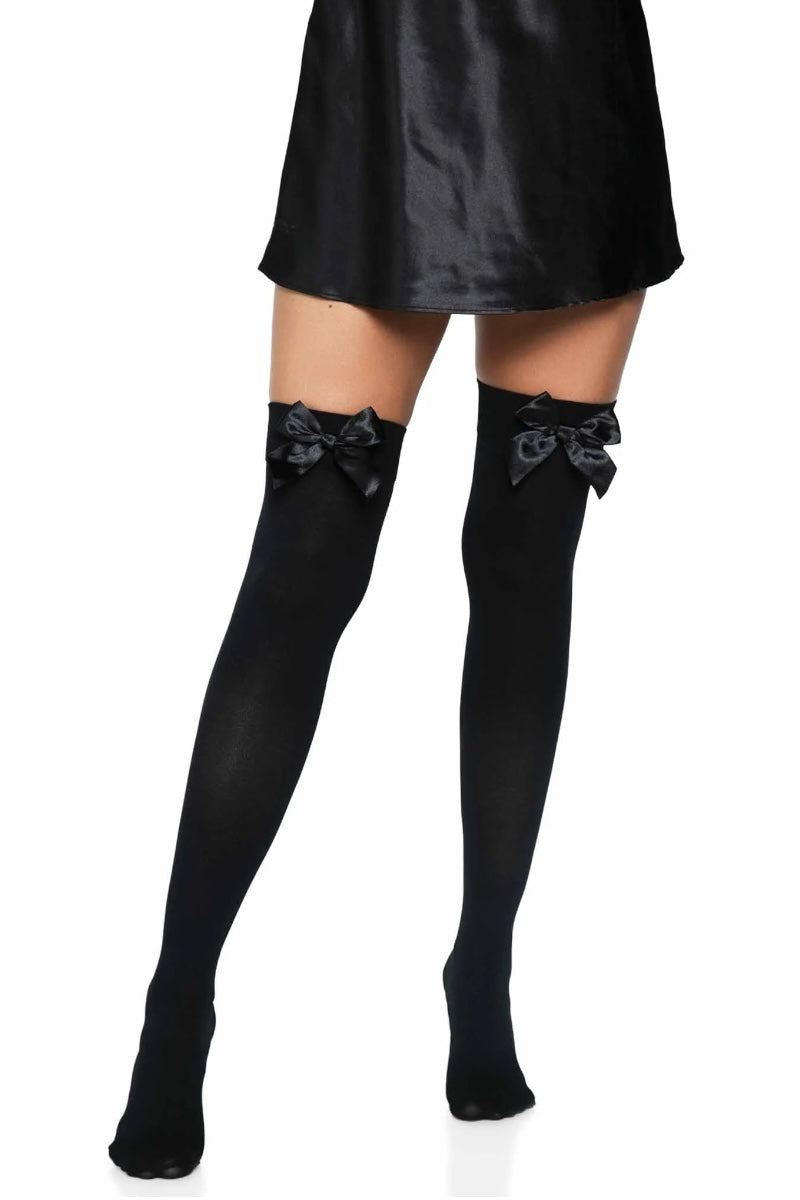 Black thigh-high stockings with bow details worn by a person on a white background