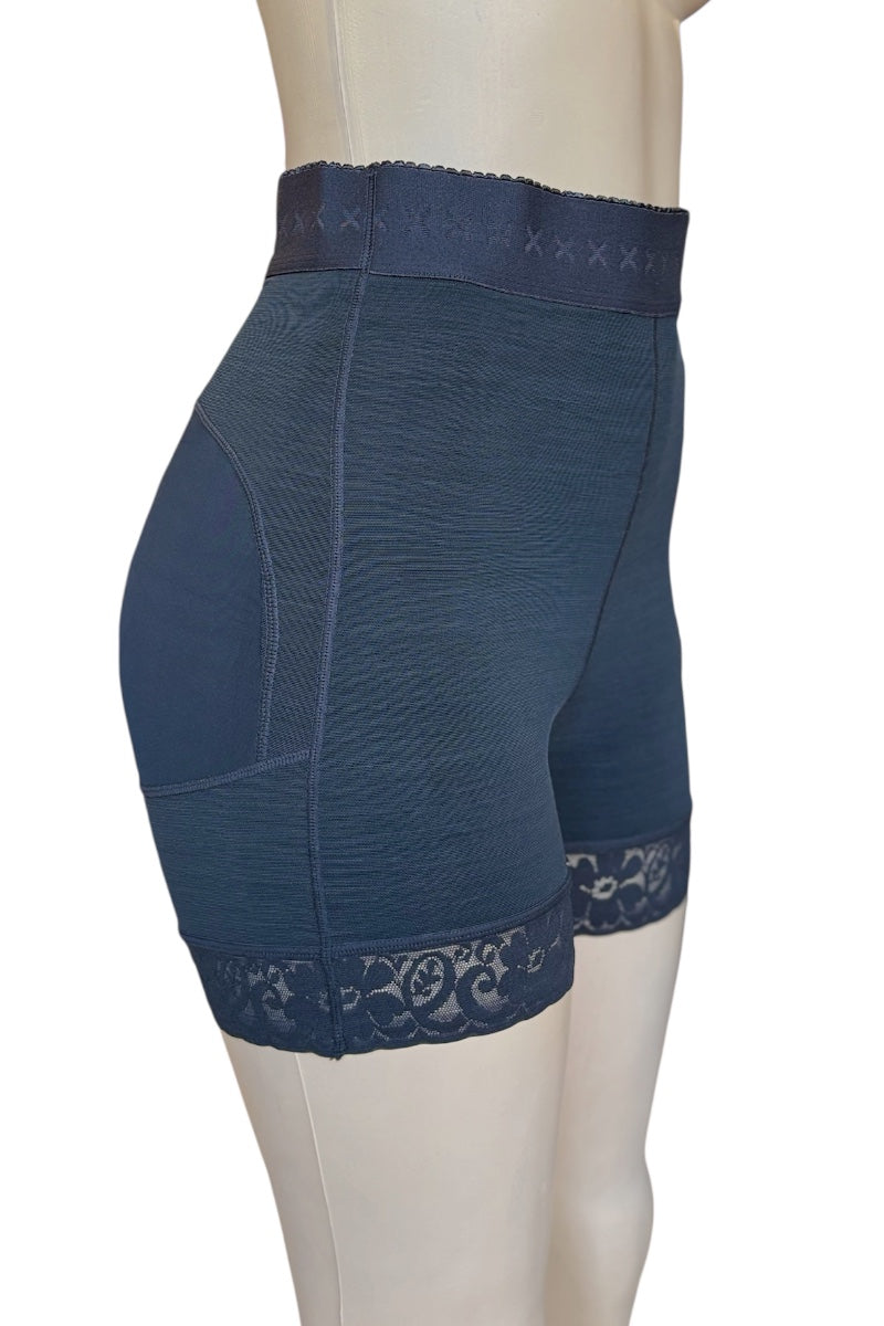 High-waisted compression shorts in black, shown on a mannequin from a side-back angle. The shorts feature a textured fabric, a lace trim at the hem, and a lace waistband with embroidered details.