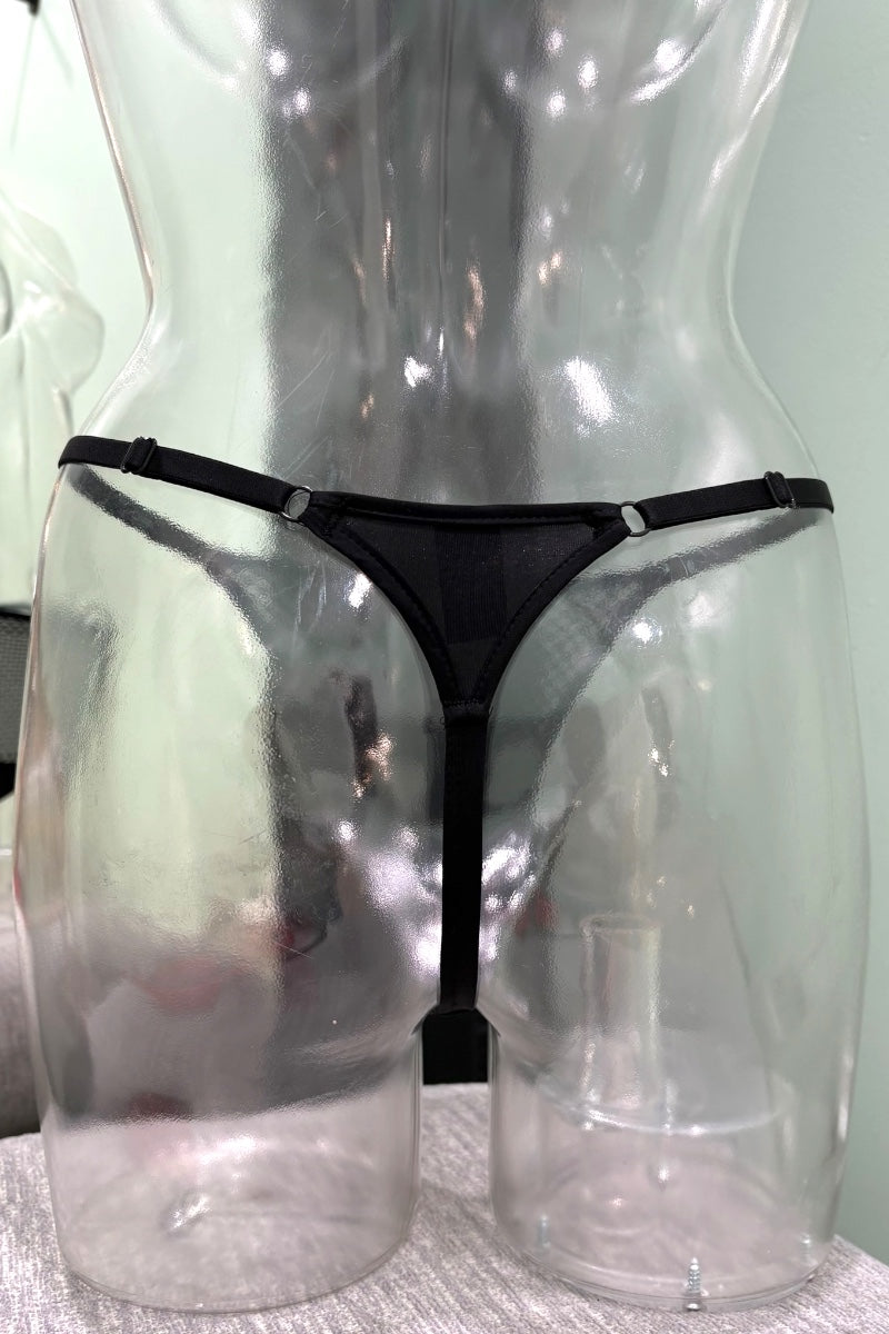 Black thong underwear displayed on a clear plastic mannequin torso against a pale green wall.