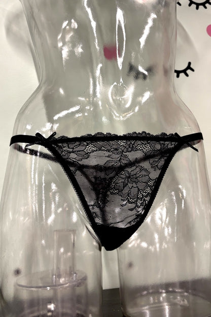 Black lace thong underwear displayed on a clear plastic female mannequin torso against a light background.