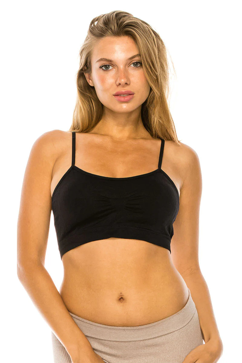 Woman wearing a black bralette and beige pants on a white background