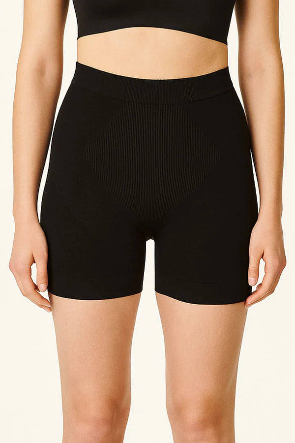 Person wearing black high-waisted shorts on a beige background