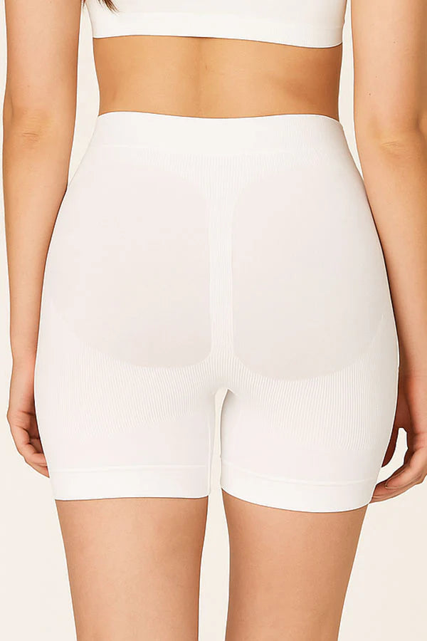 White high-waisted shorts worn by a person on a beige background