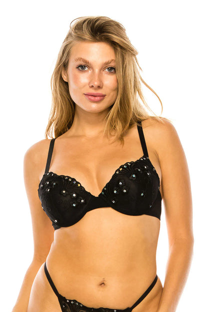Woman wearing a black bra with embellishments on a white background