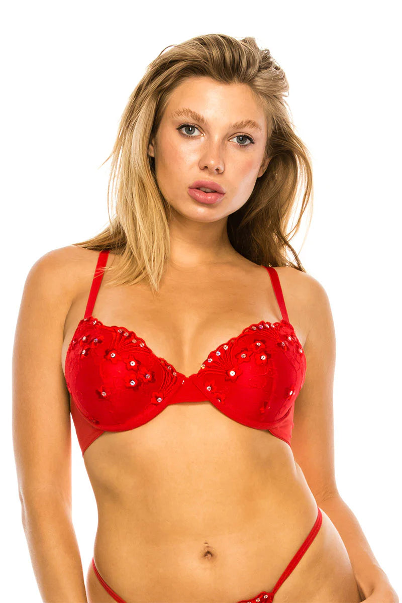 Woman wearing a red bra with embellishments on a white background