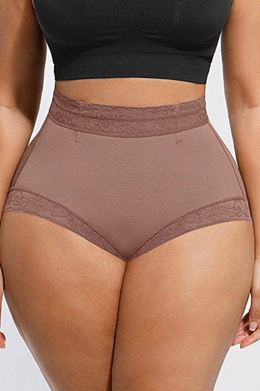 Person wearing cocoa high-waisted underwear shaper with lace trim on a plain background