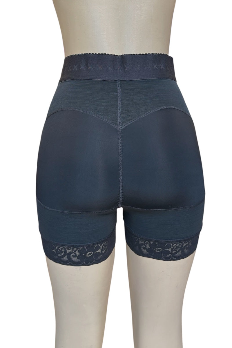 Rear view of high-waisted compression or shapewear shorts on a mannequin, in a black color with a lace hem and patterned waistband.