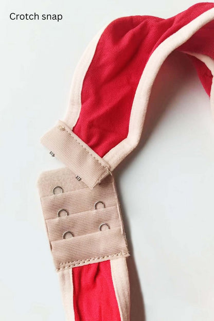 Close-up of a crotch snap on red fabric with a beige strap.