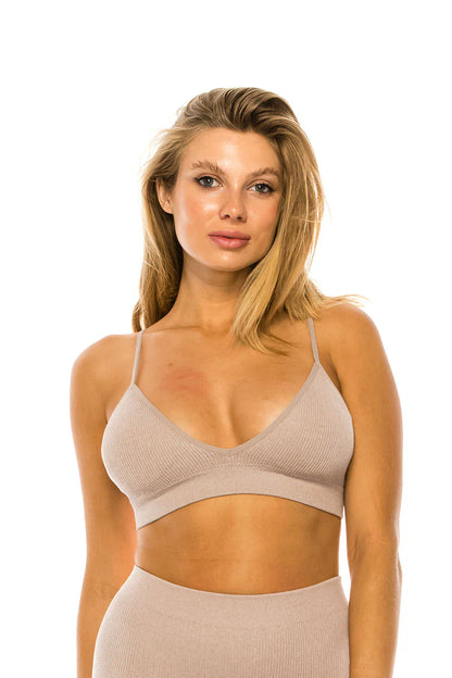 Woman wearing an oatmeal sports bra and leggings on a white background