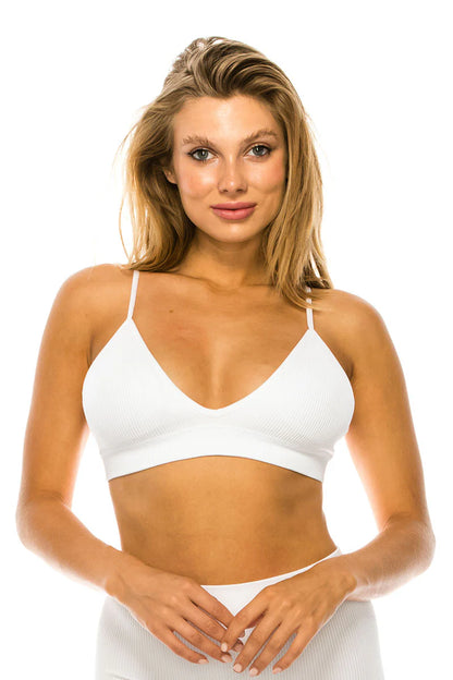 Woman wearing a white sports bra and shorts on a white background