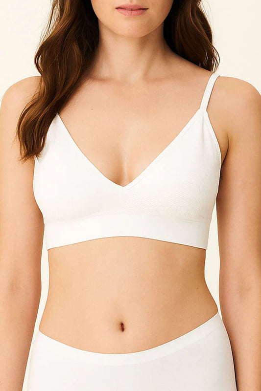 Woman wearing a white bra against a plain background