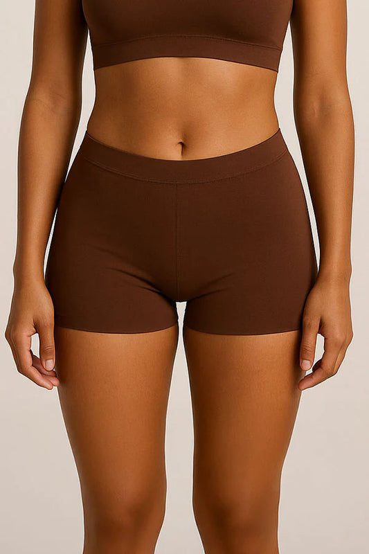 Person wearing brown shorts and crop top on a beige background