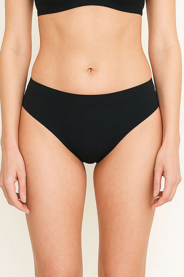 Person wearing black high-waisted bikini bottoms on a plain background