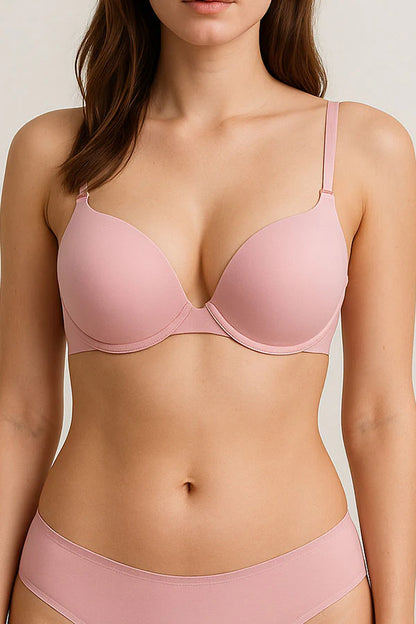 Woman wearing a pink bra and underwear set against a neutral background