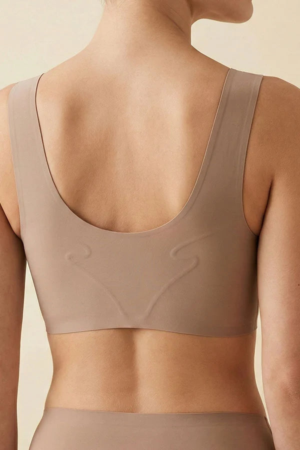 Rear view of a model wearing a seamless, scoop-neck bra in a taupe beige color, showing the molded back design.