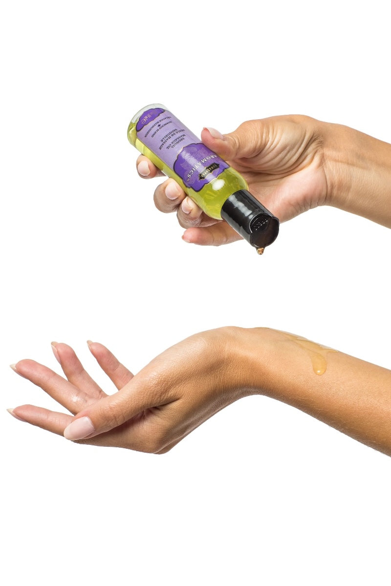 Hand holding a bottle of green liquid with a purple label against a white background