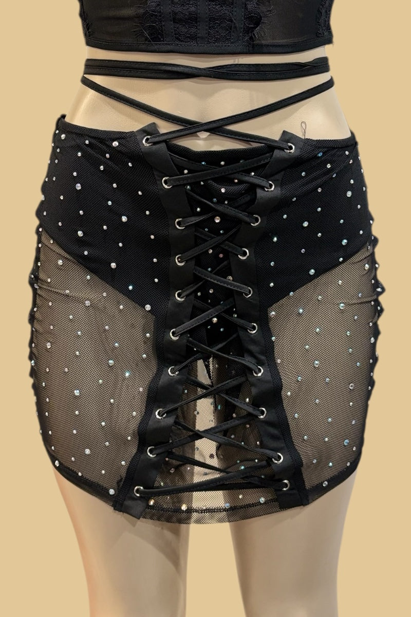 Black lace-up skirt with sheer overlay on a beige background