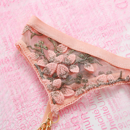 Pink lace garter belt with floral embroidery on a pink background